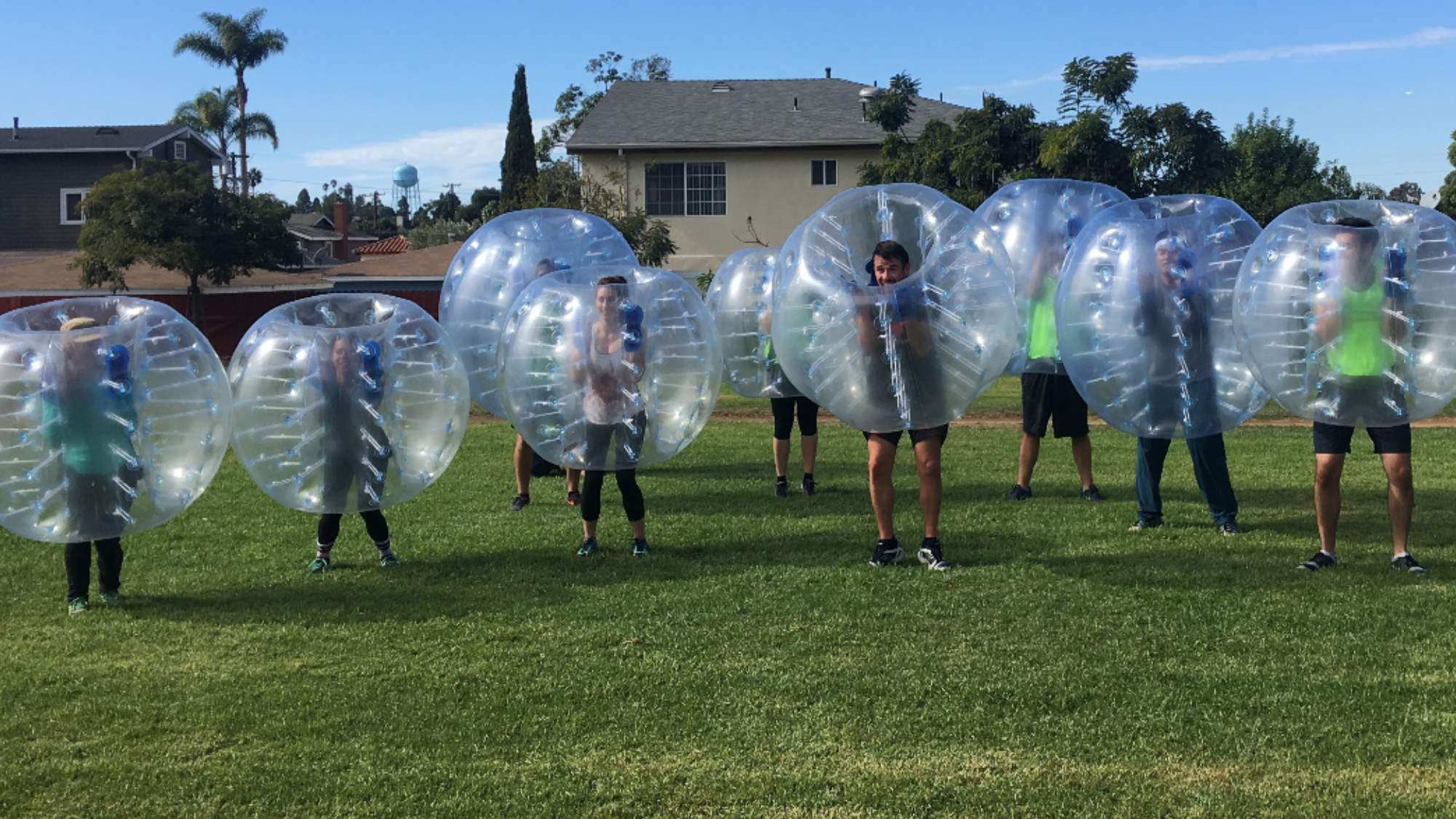 Team lined up in bubble suits on green grass field