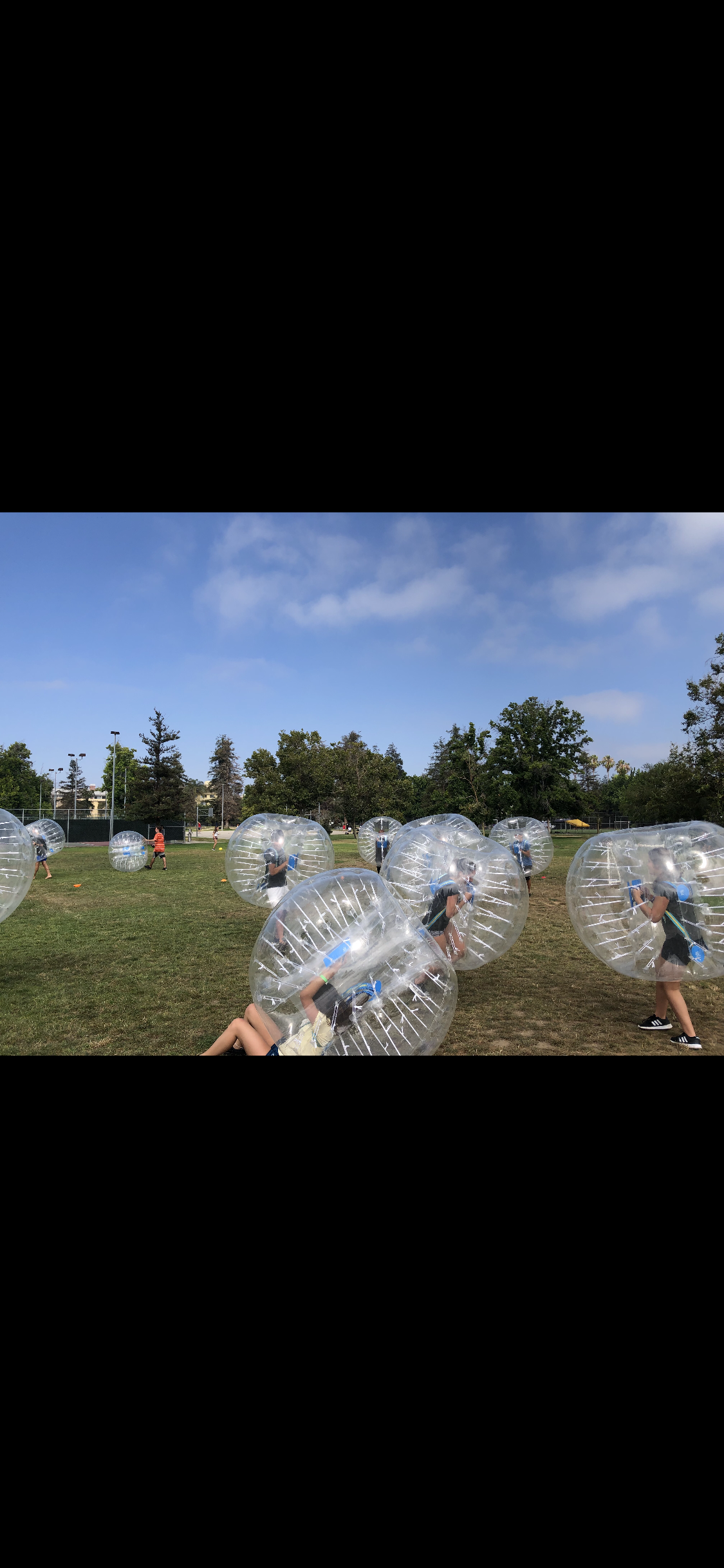 Players in bubble suits on grass field at outdoor event
