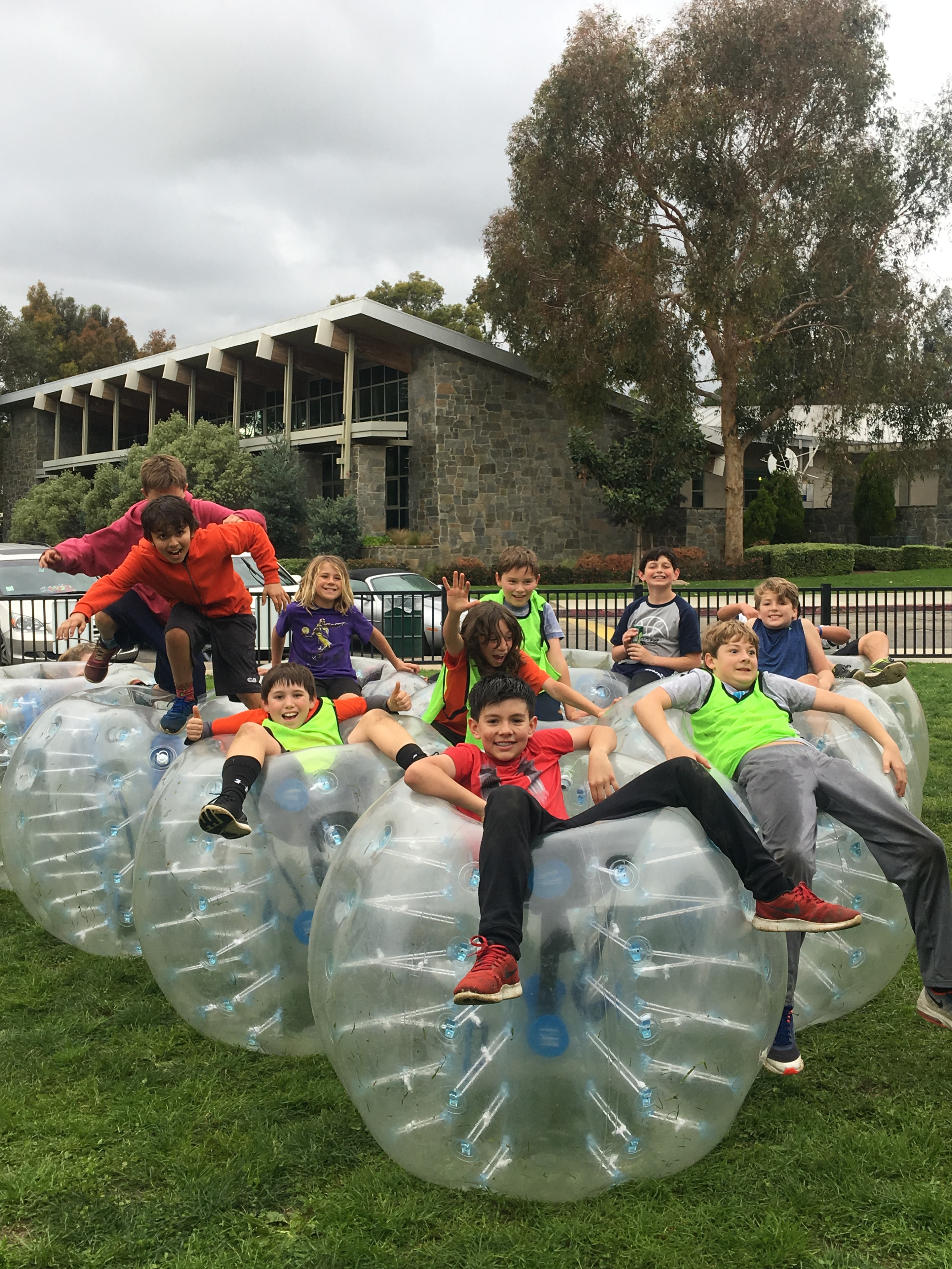 Children posing on top of bubble suits at outdoor event