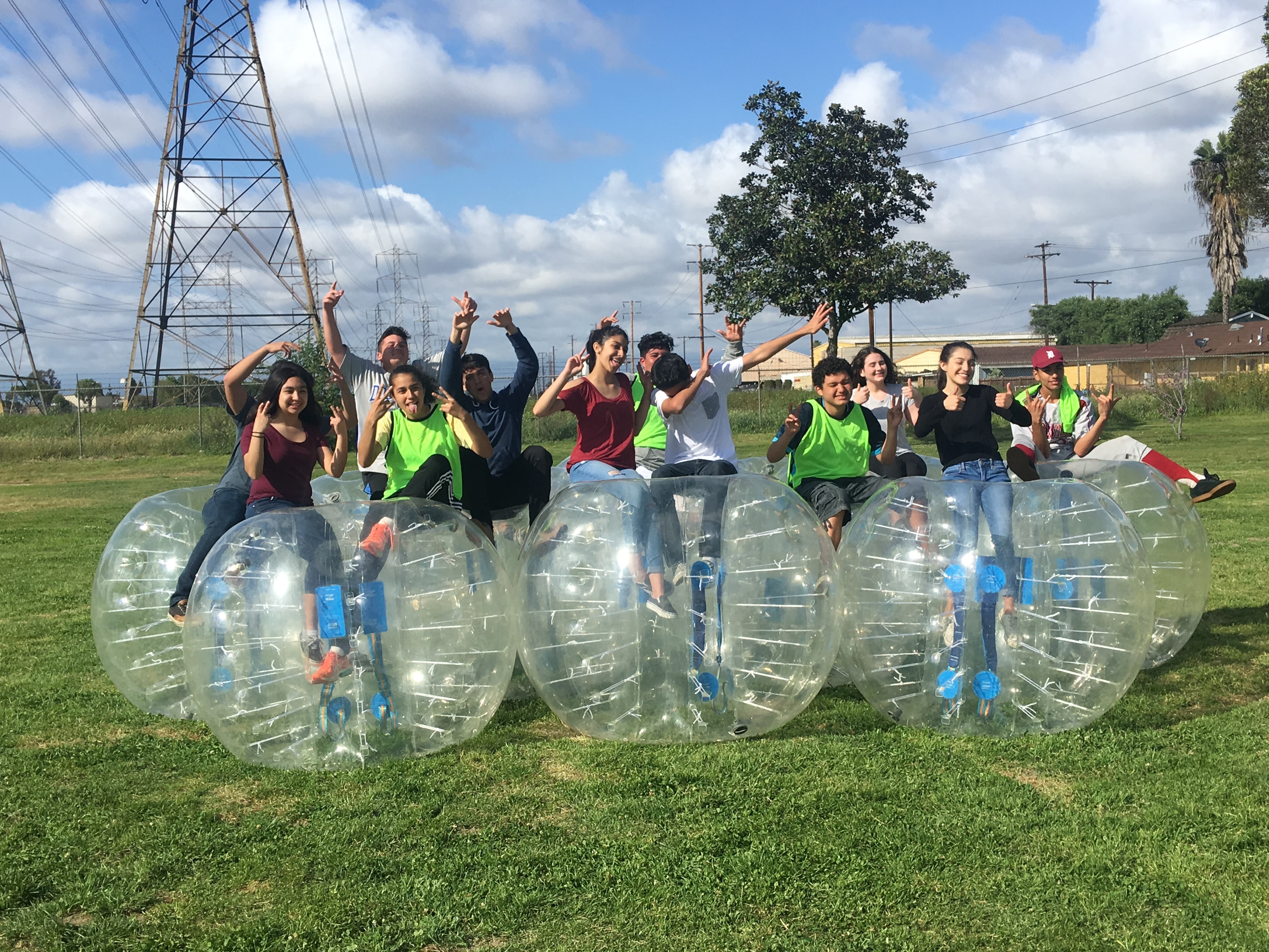 Group of teens in bubble suits on grass field