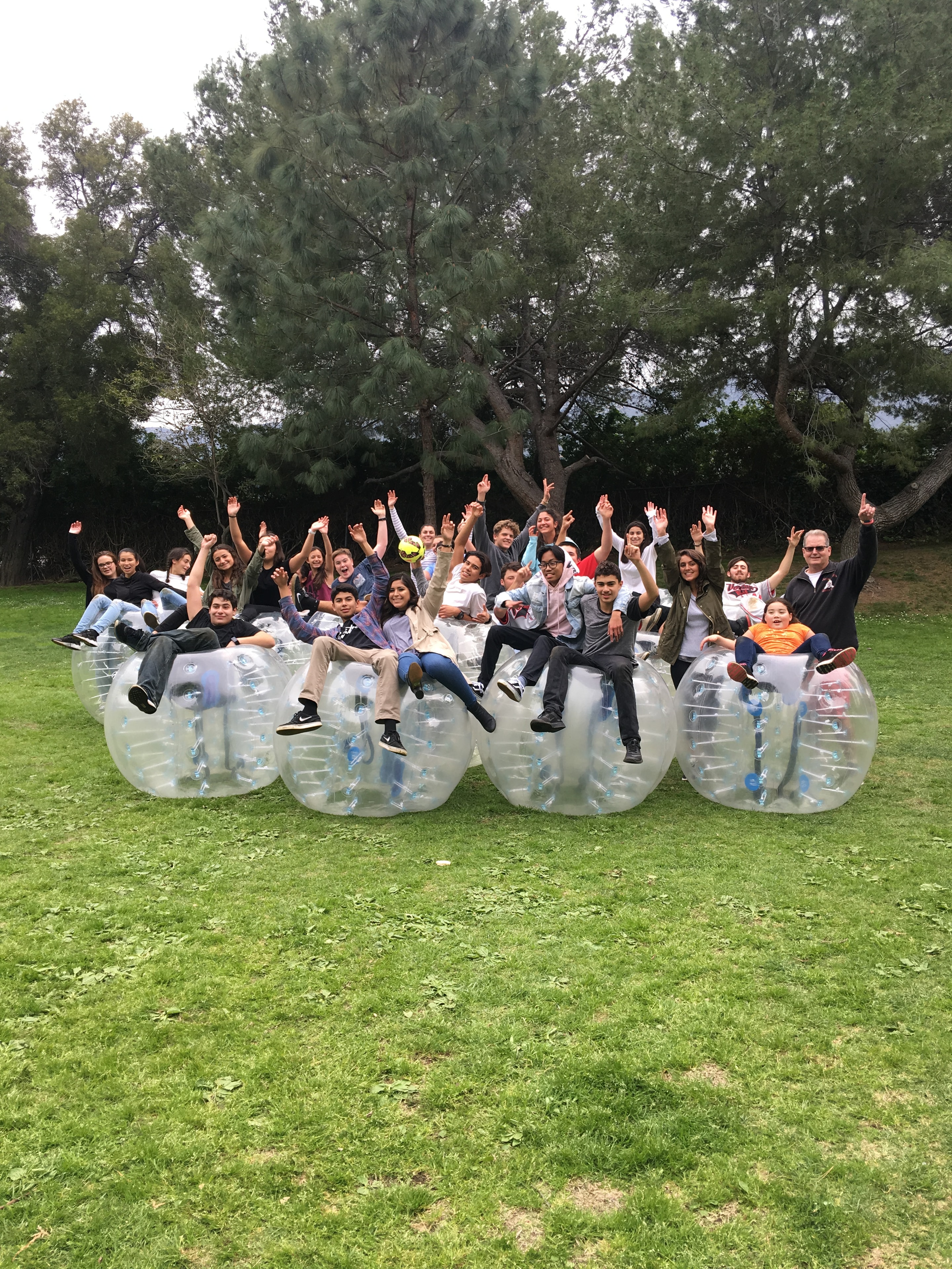 Large group posing with bubble suits at park event