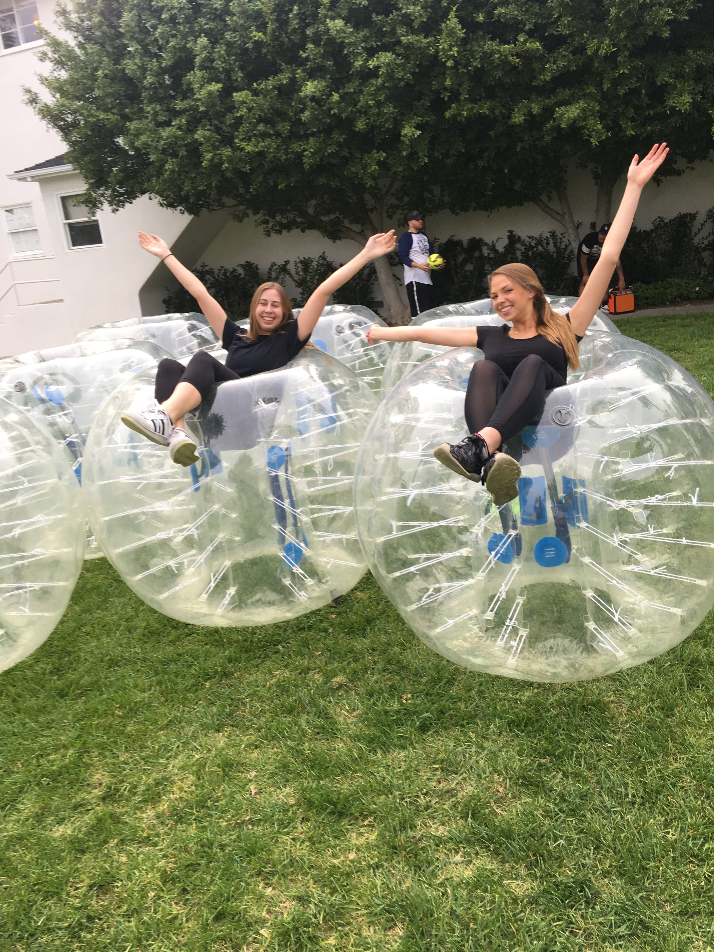 Two women on top of bubble suits having fun outdoors